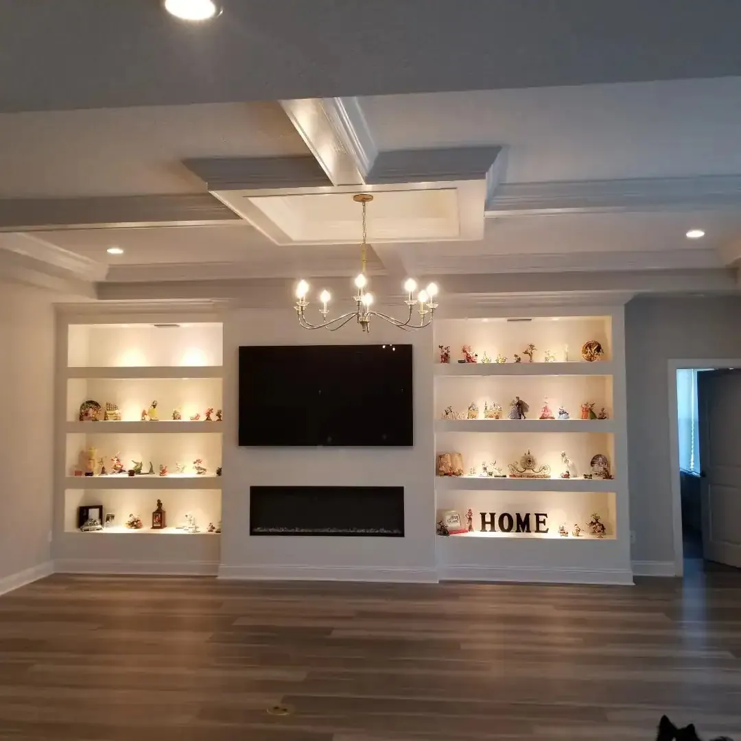 Painted built-in cabinets with lighted shelf niches beneath a coffered ceiling